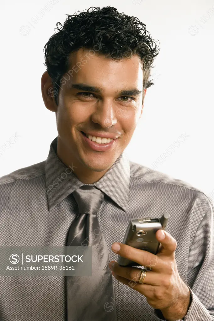Studio shot of Hispanic businessman holding cell phone