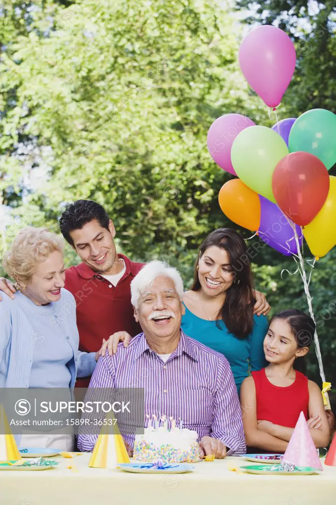 Senior Hispanic man with family and birthday cake