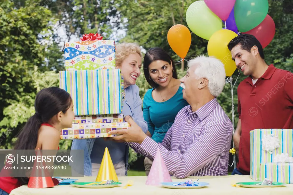 Senior Hispanic man receiving gifts at birthday party