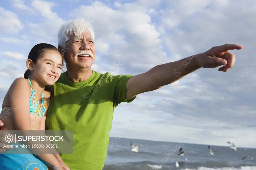 Hispanic grandfather with granddaughter pointing into the distance