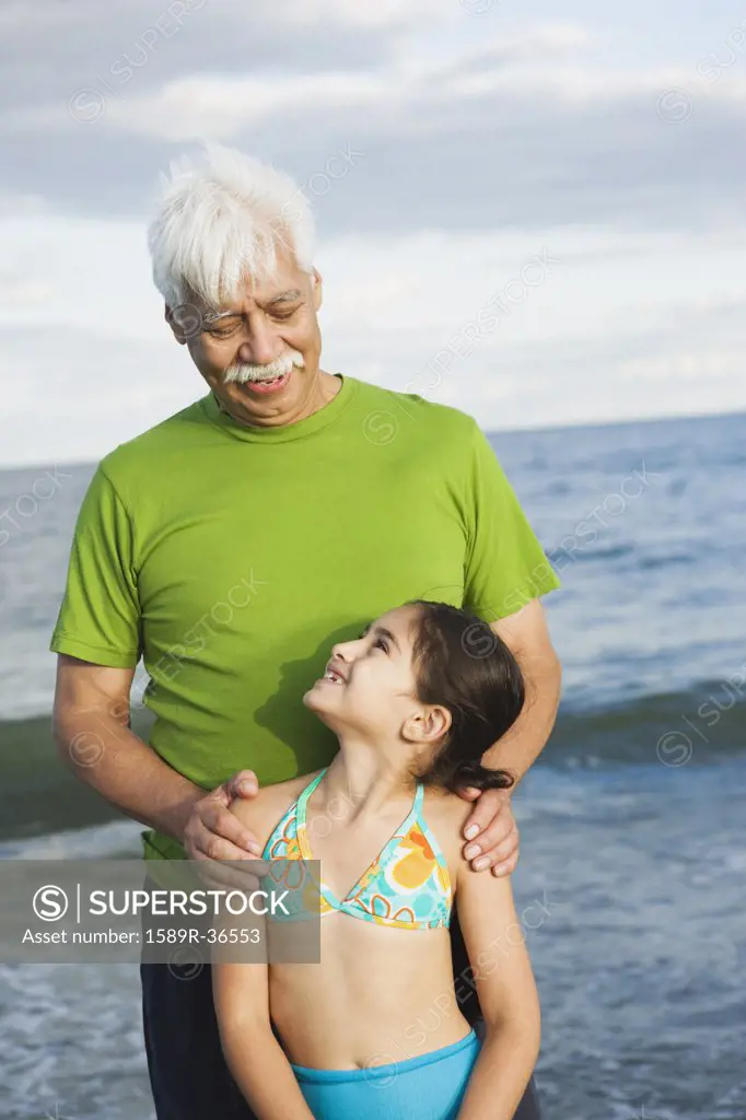 Hispanic grandfather and granddaughter at beach