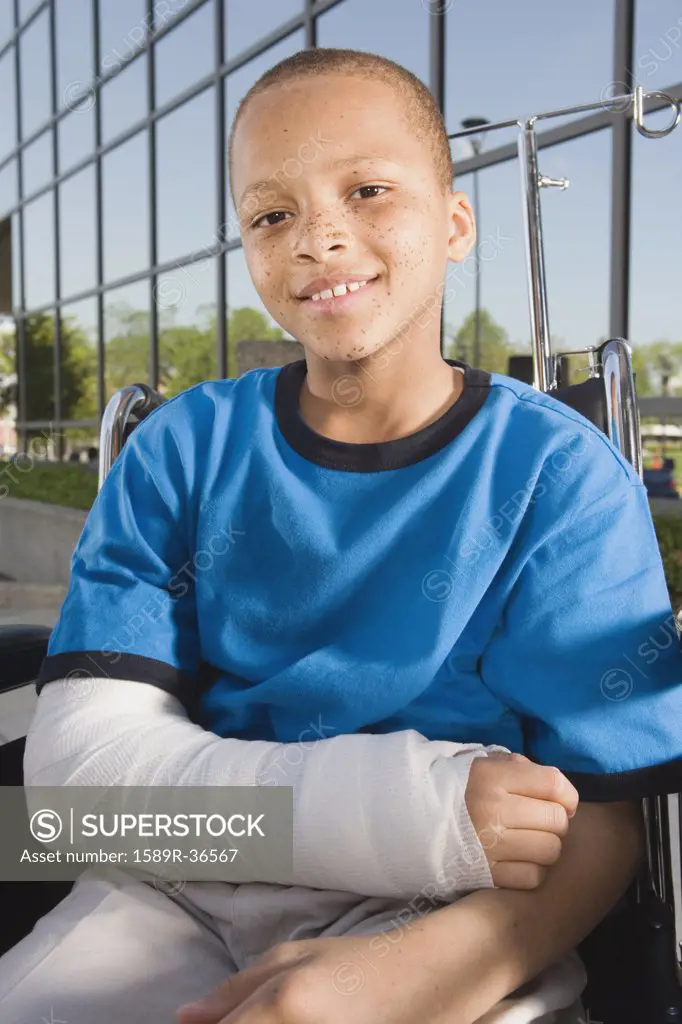 Close up of African boy with broken arm in wheelchair outdoors