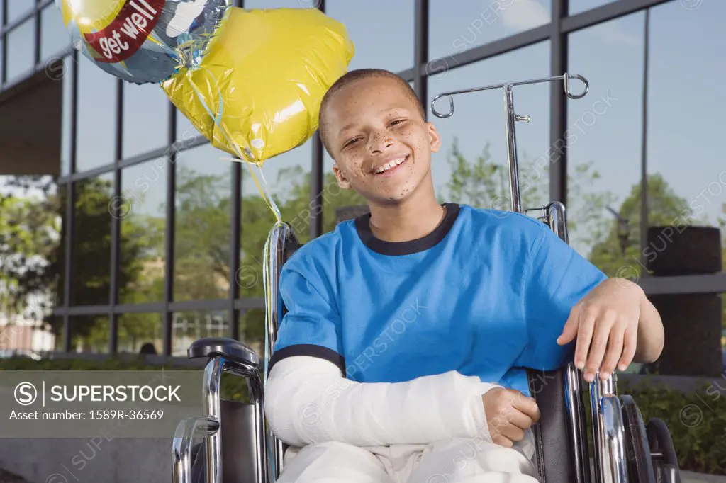 African boy with broken arm and balloons in wheelchair 