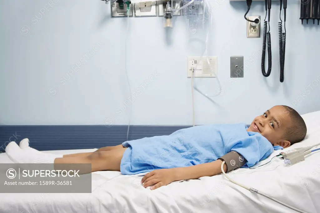 African boy in hospital bed with blood pressure cuff 