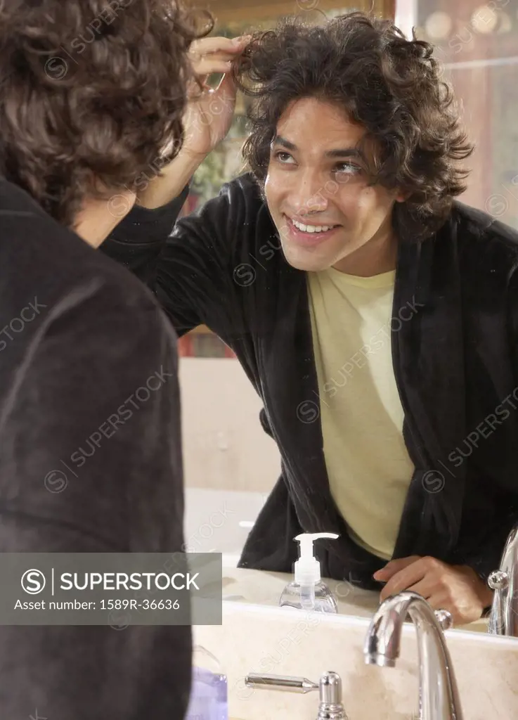 Hispanic man looking in bathroom mirror