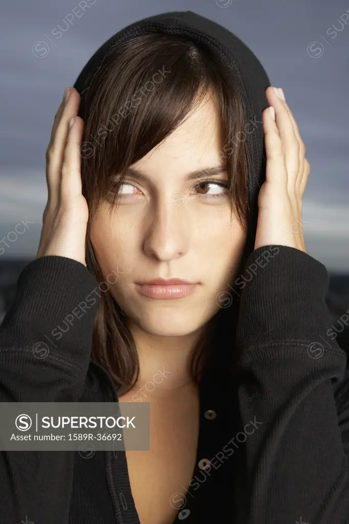 Hispanic woman covering ears with hands