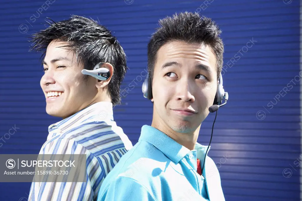 Two young men back to back wearing headsets