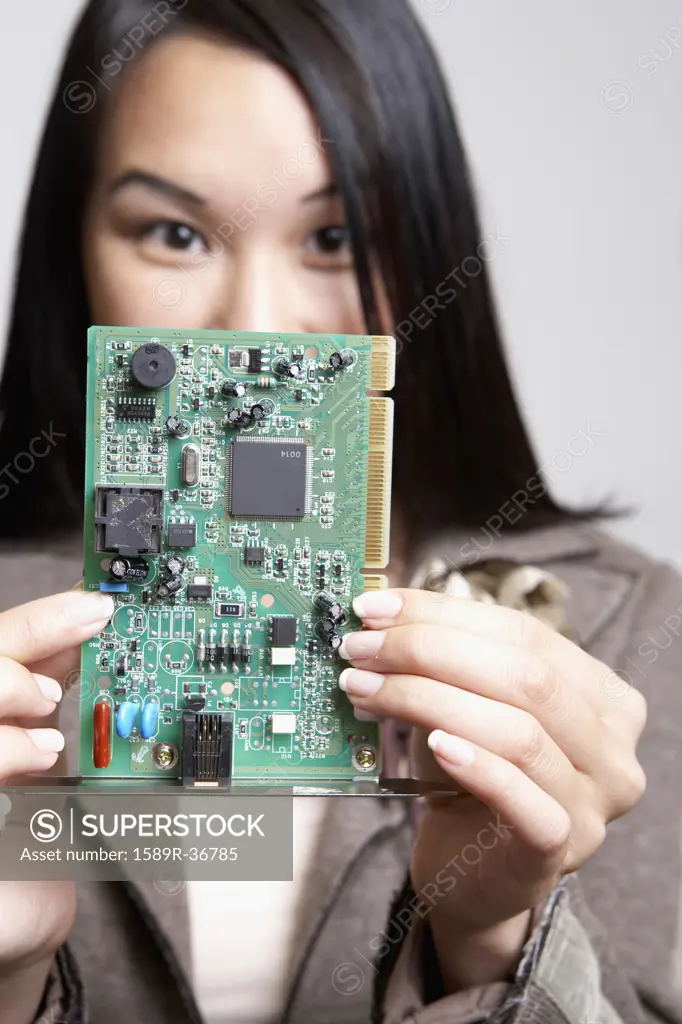 Asian businesswoman holding up computer circuit board