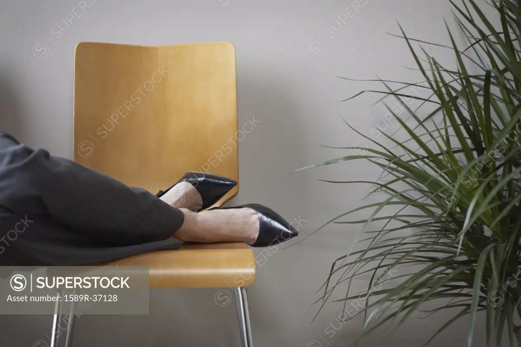 Close up of businesswomans feet on chair