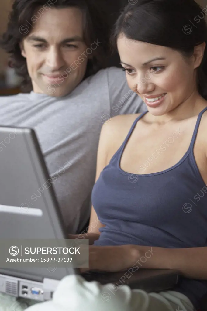 Multi-ethnic couple looking at laptop