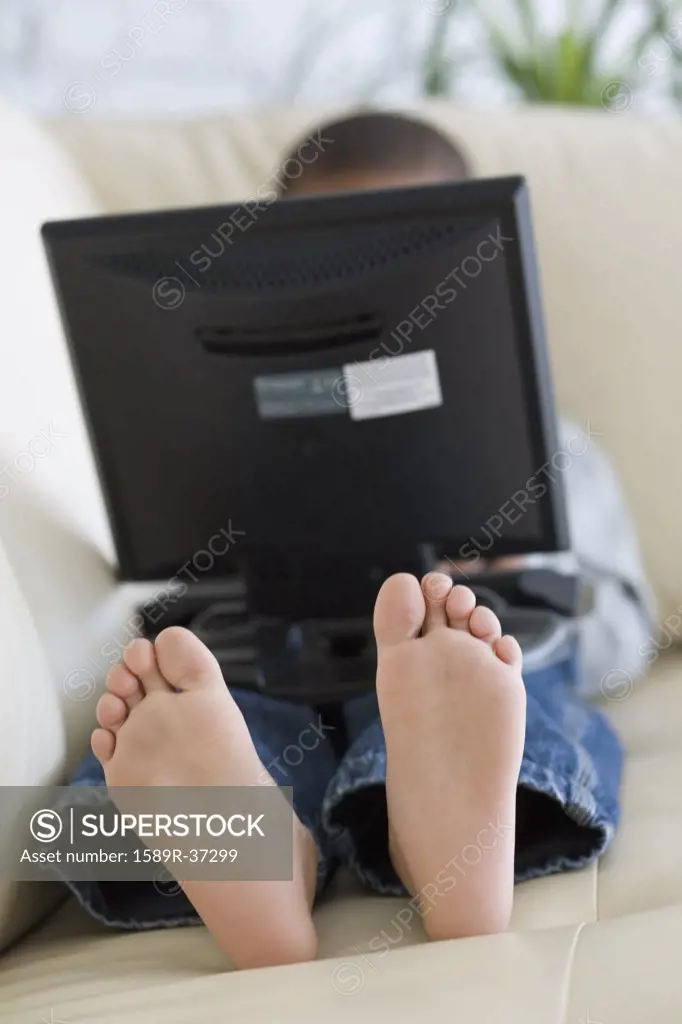 African boy using laptop on sofa