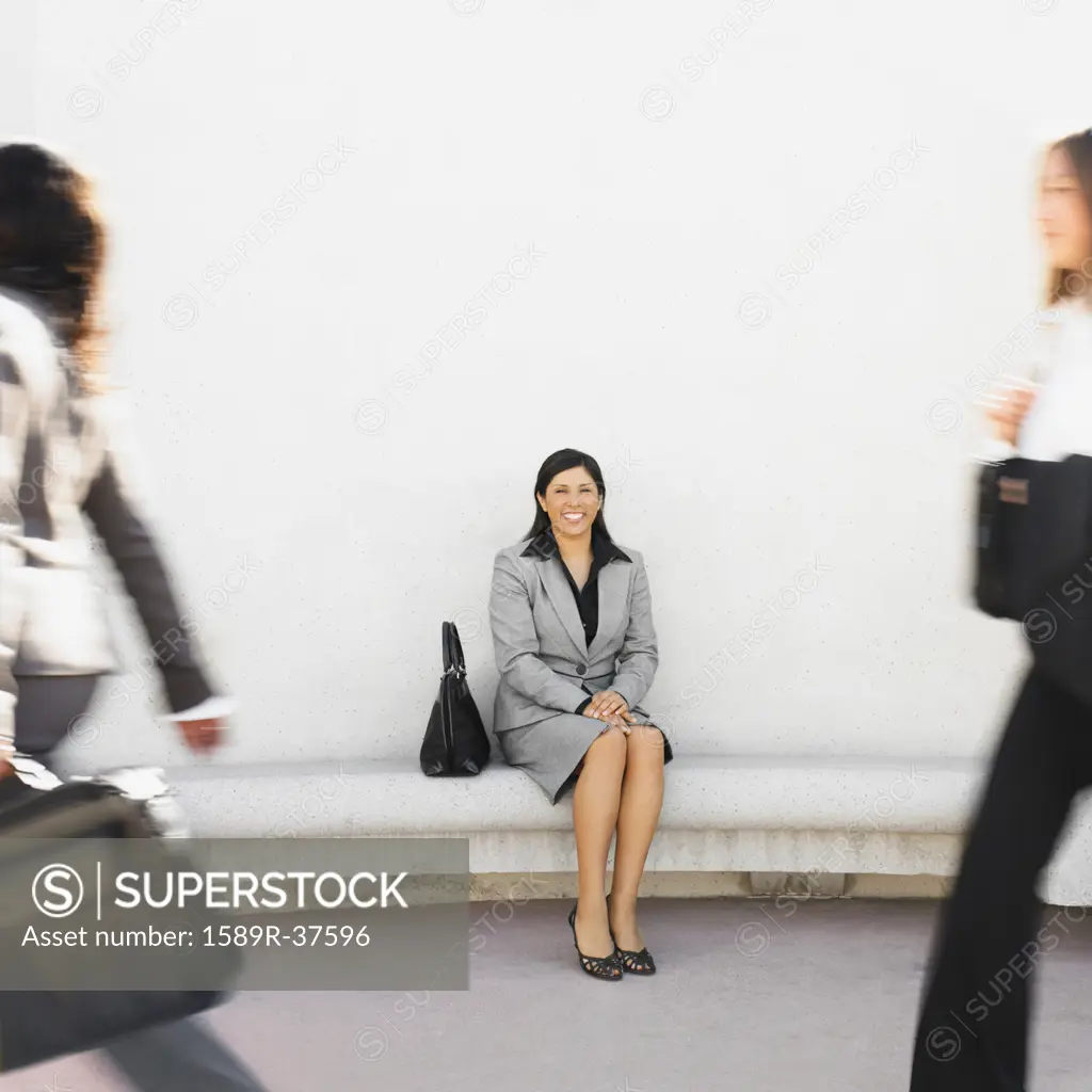 Hispanic businesswoman sitting outdoors