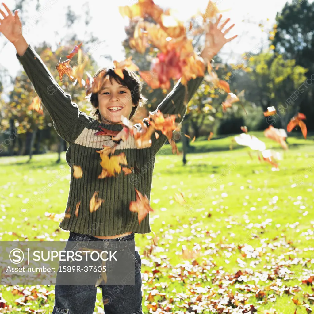 Mixed Race boy playing in autumn leaves