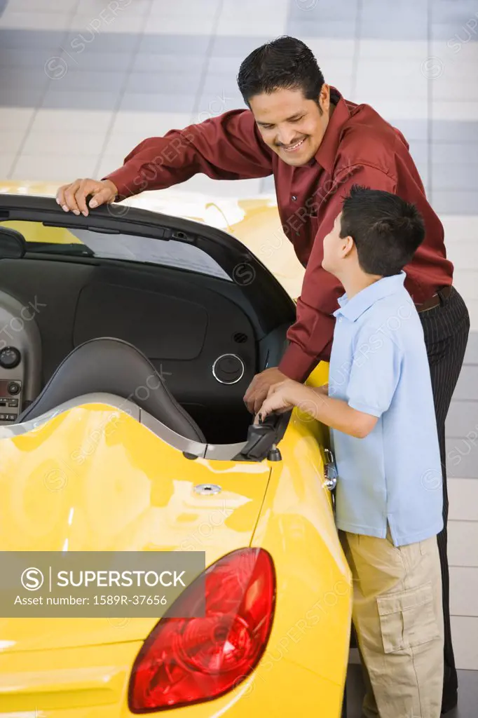 Hispanic father and son looking at new car