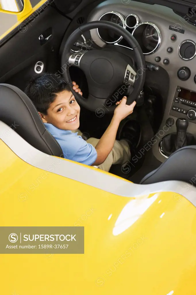 Hispanic boy sitting in new car