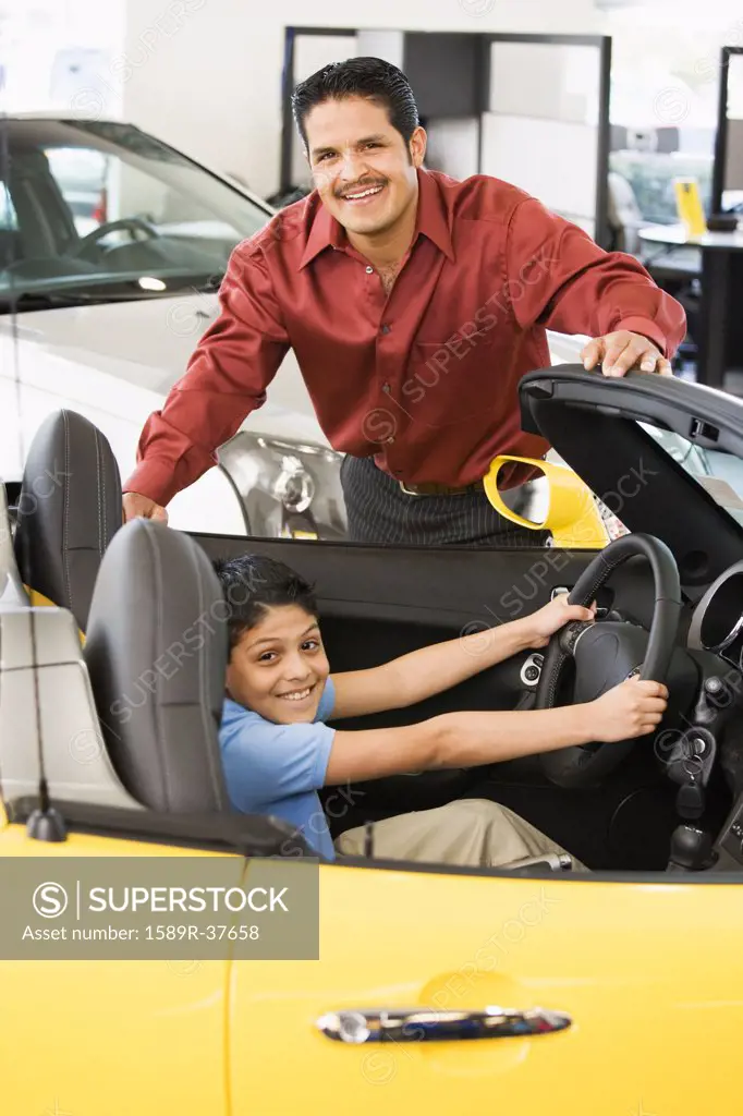 Hispanic father and son looking at new car