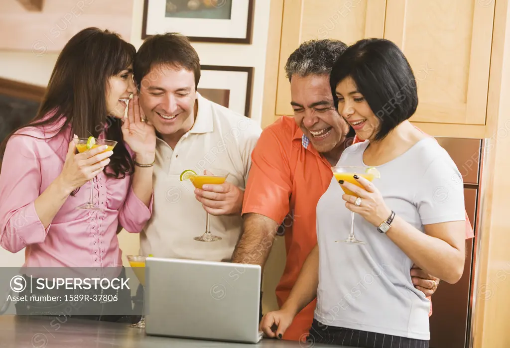 Two middle-aged couples looking at laptop