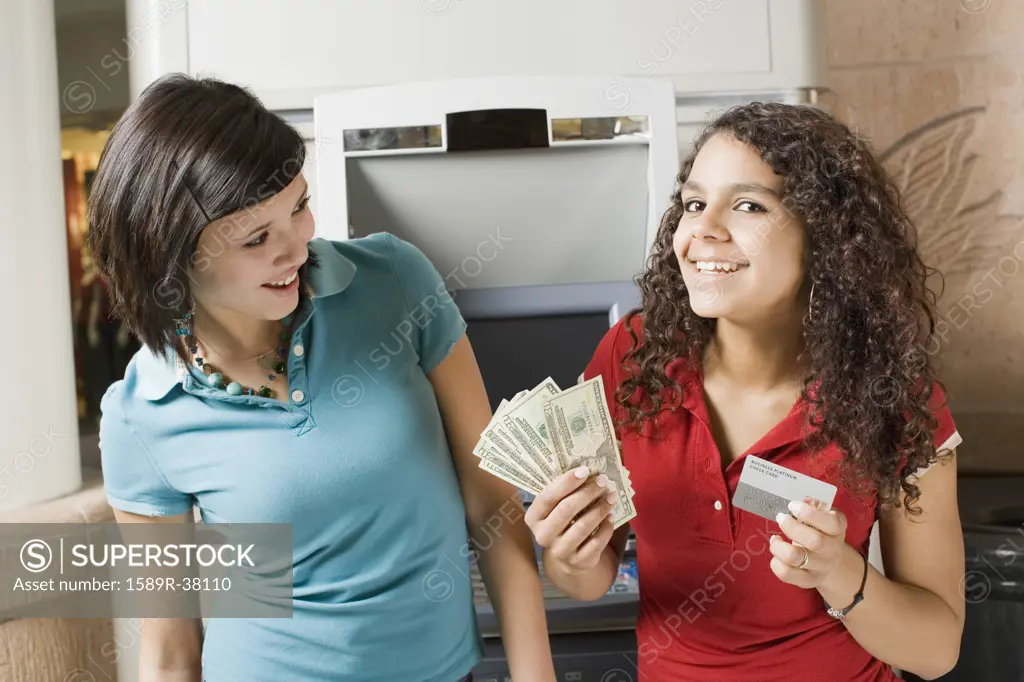 Multi-ethnic teenage girls holding money and credit card