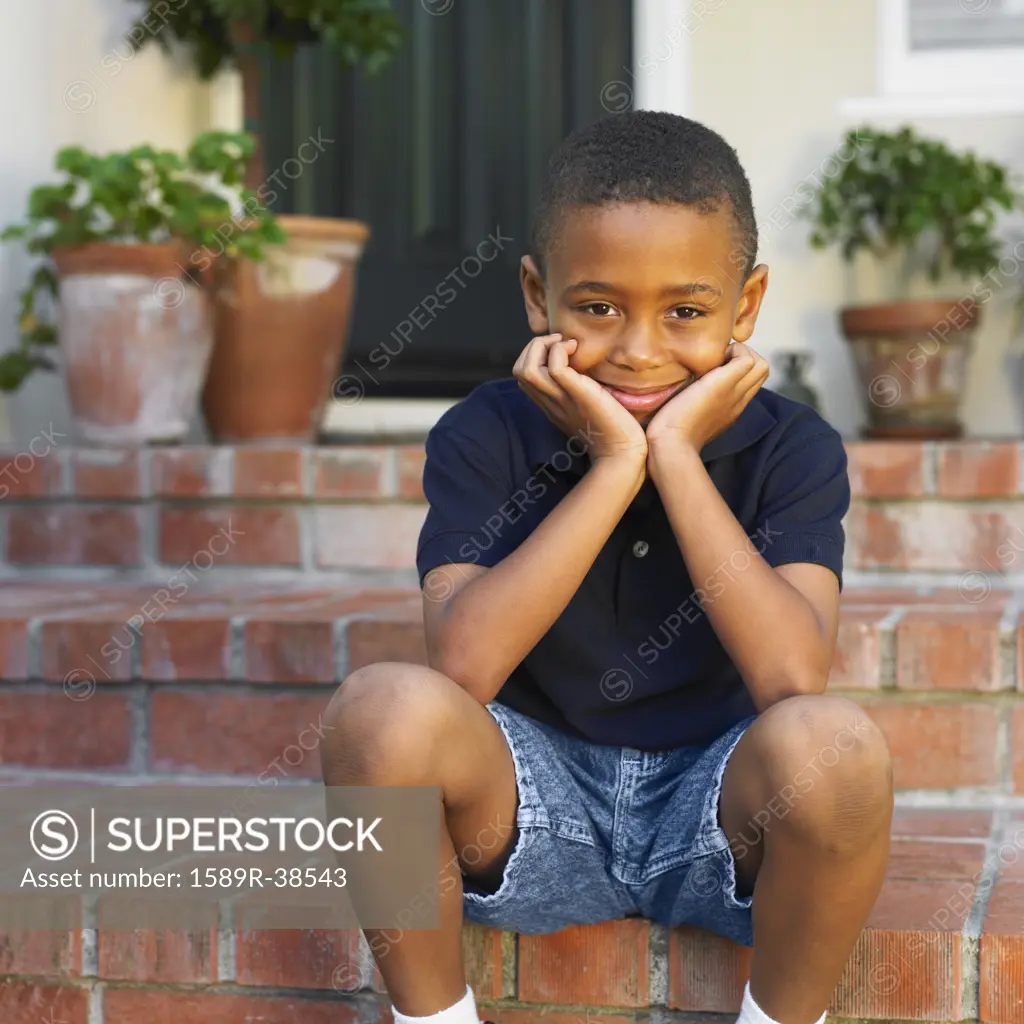 African boy sitting on porch steps