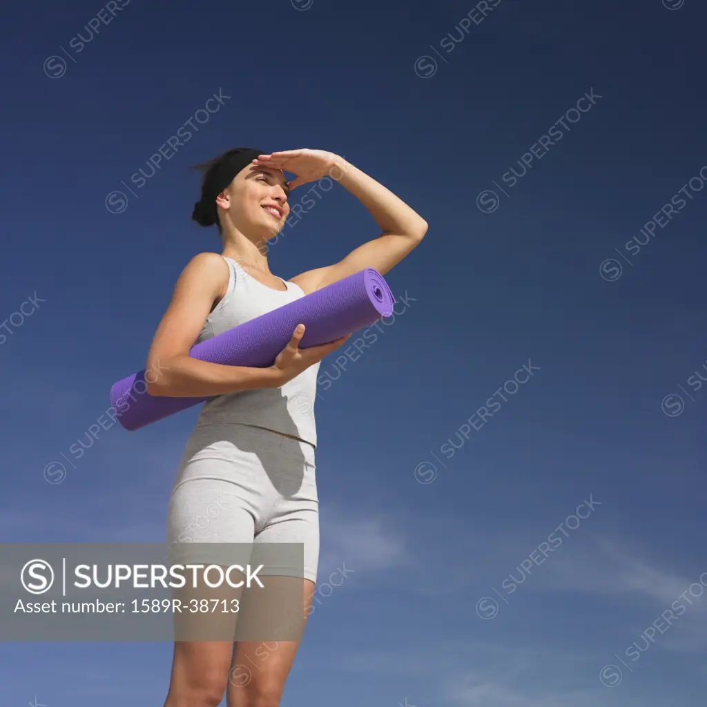 Mixed Race woman holding yoga mat