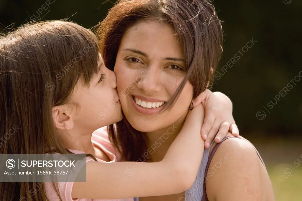 Hispanic girl kissing mother on cheek