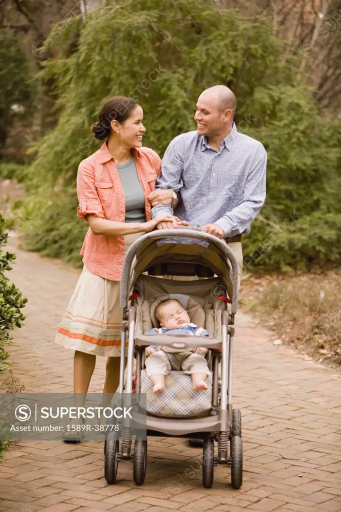 Hispanic parents pushing baby in stroller