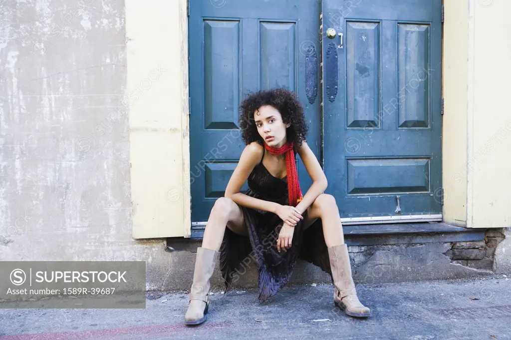 Mixed Race woman sitting in doorway