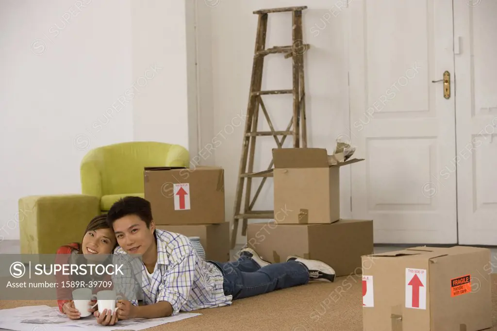 Asian couple on floor next to moving boxes