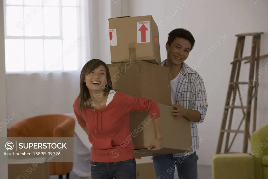Asian couple carrying moving boxes