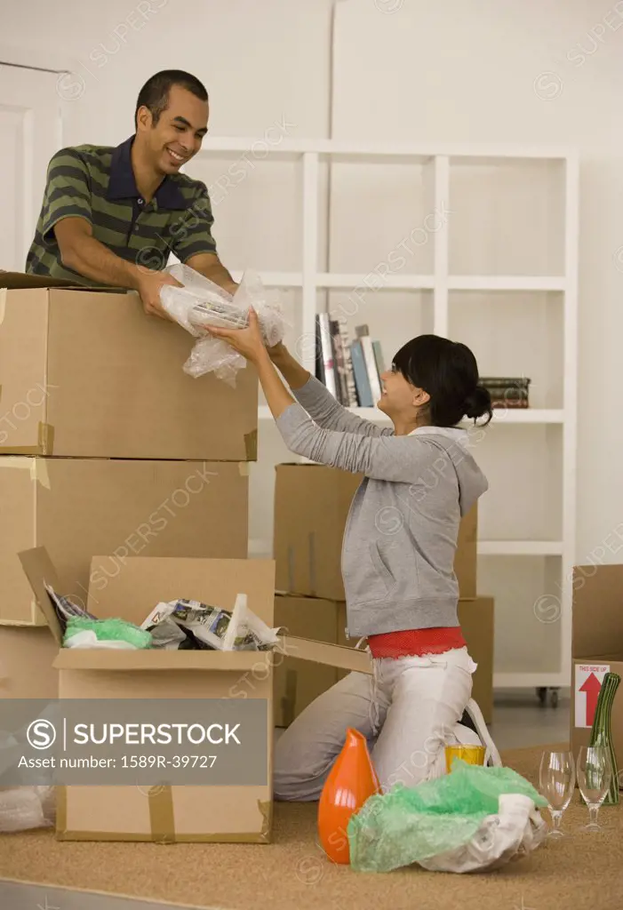 Young couple packing moving boxes