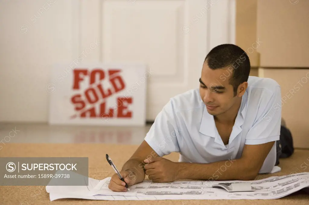 Man writing on blueprints in new house