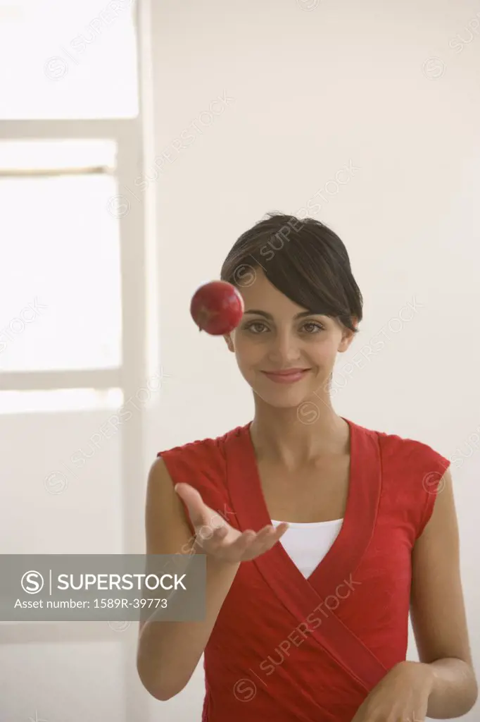 Young woman throwing apple in air
