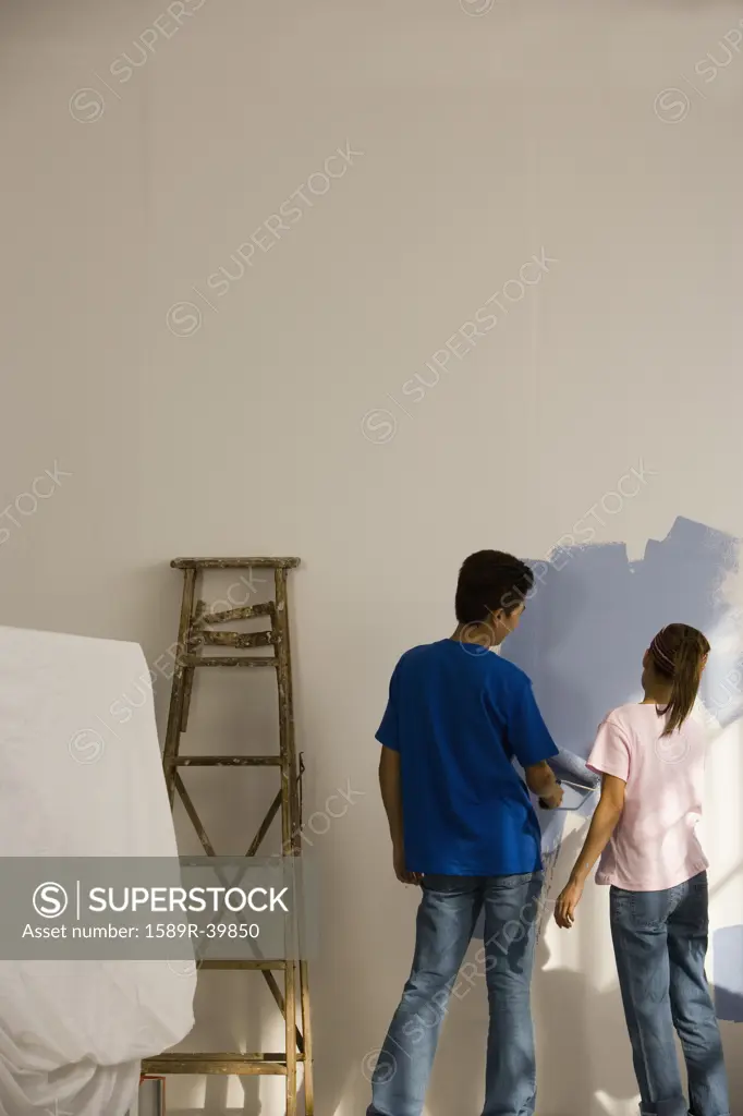 Asian couple painting interior of house