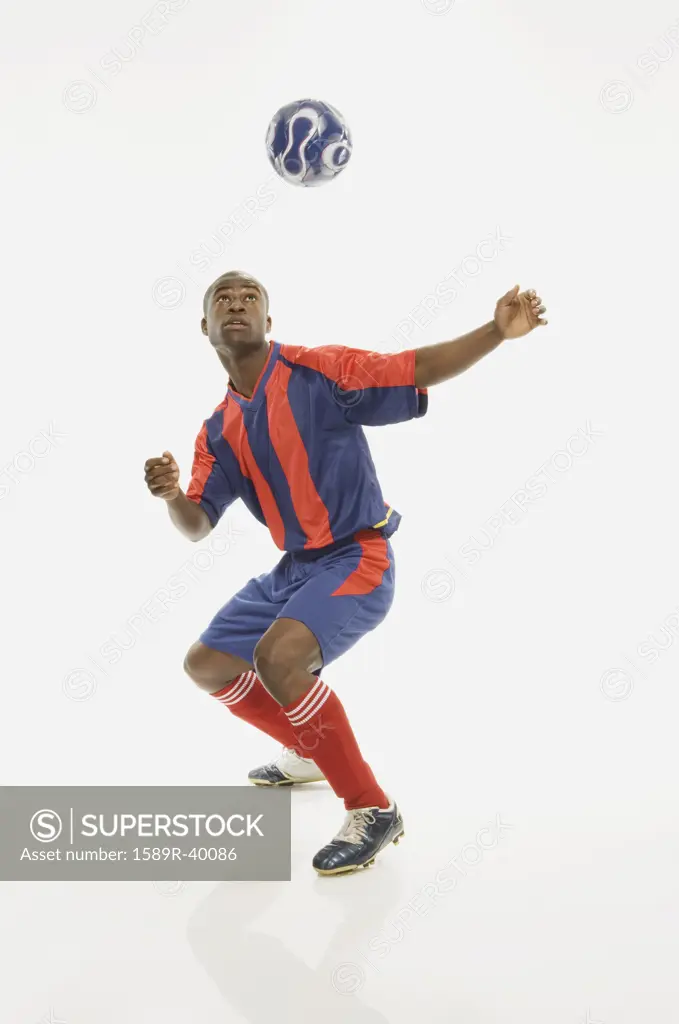 African American male soccer player with ball in air