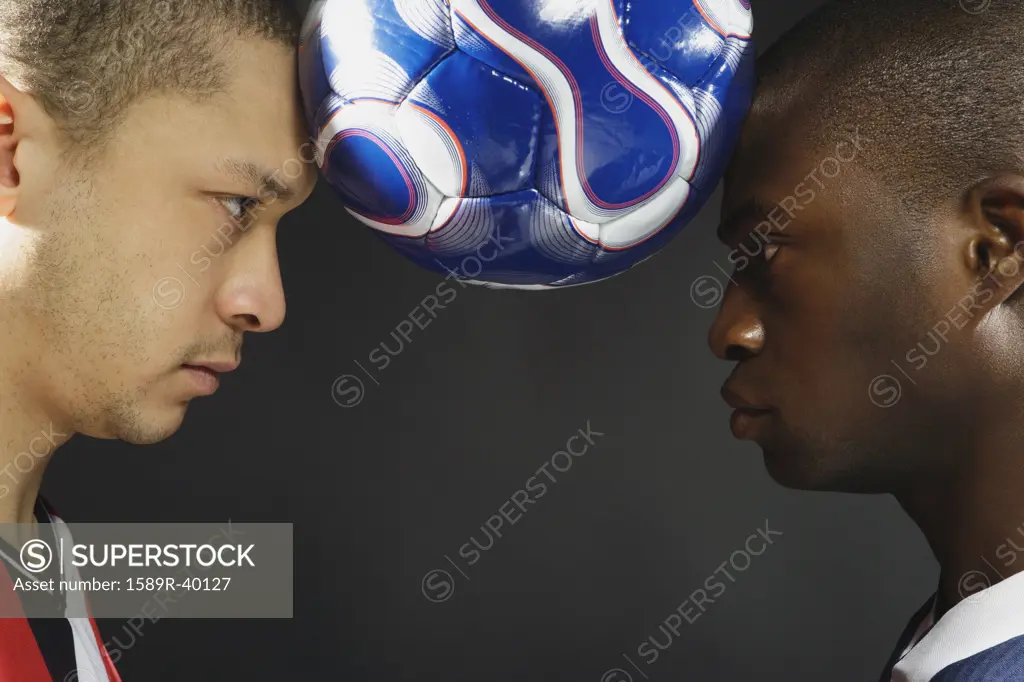 Multi-ethnic men holding soccer ball between heads