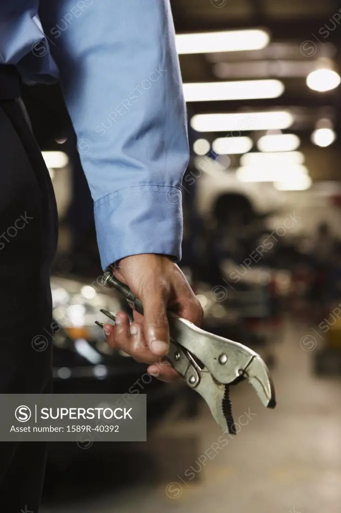 Male auto mechanic holding vice grips