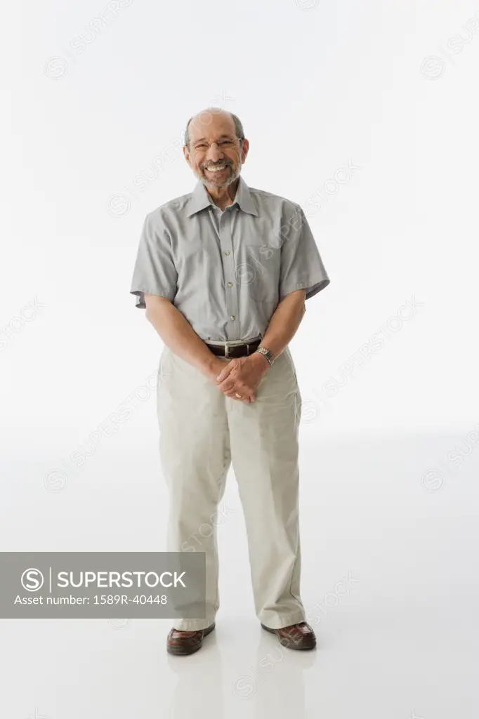 Senior man standing with hands clasped