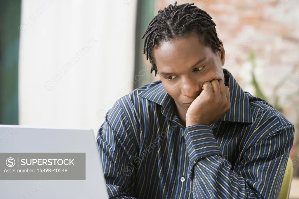 African man looking at laptop
