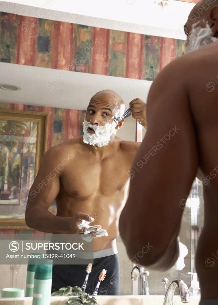 Mixed Race man shaving in bathroom