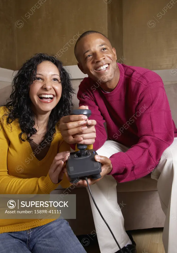 Multi-ethnic couple playing video game