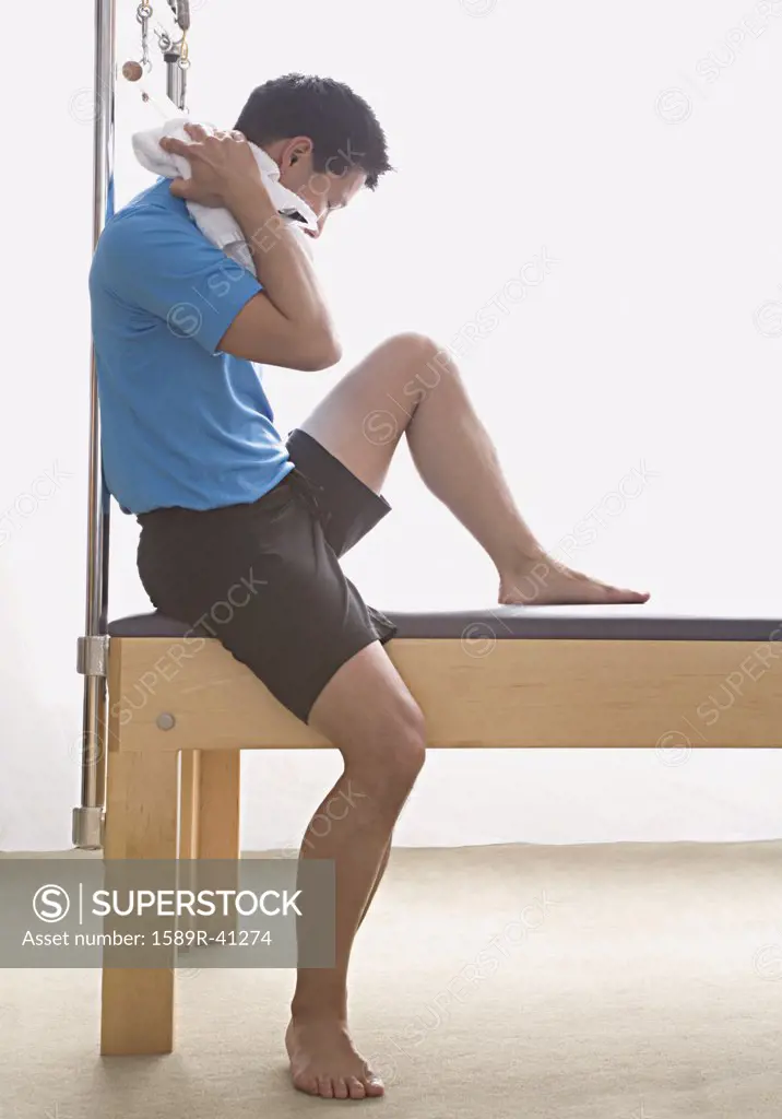 Asian man sitting on exercise equipment