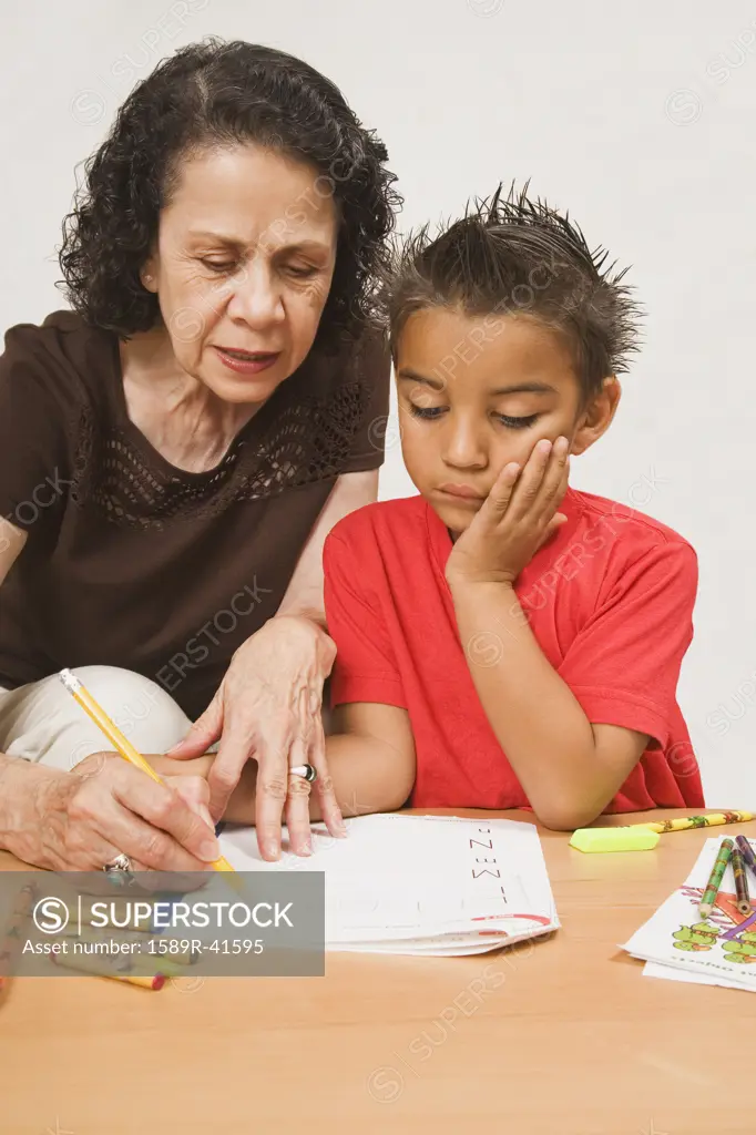 Hispanic grandmother helping grandson with homework