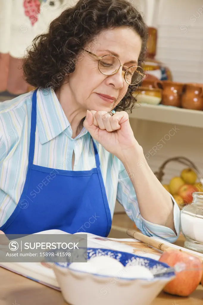 Senior Hispanic woman reading cook book