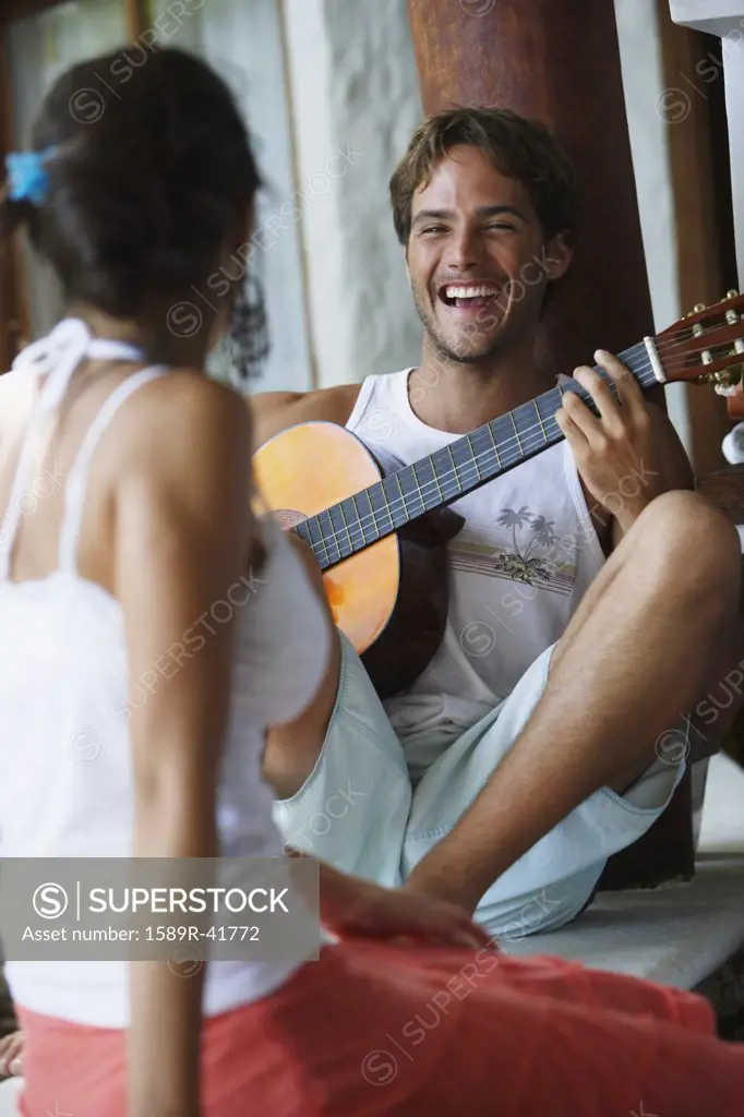 South American man playing guitar for girlfriend