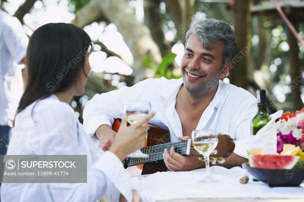 South American man playing guitar for wife