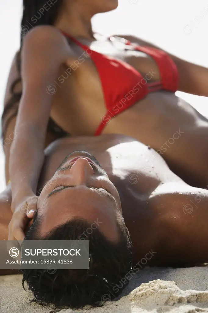 South American couple laying on beach