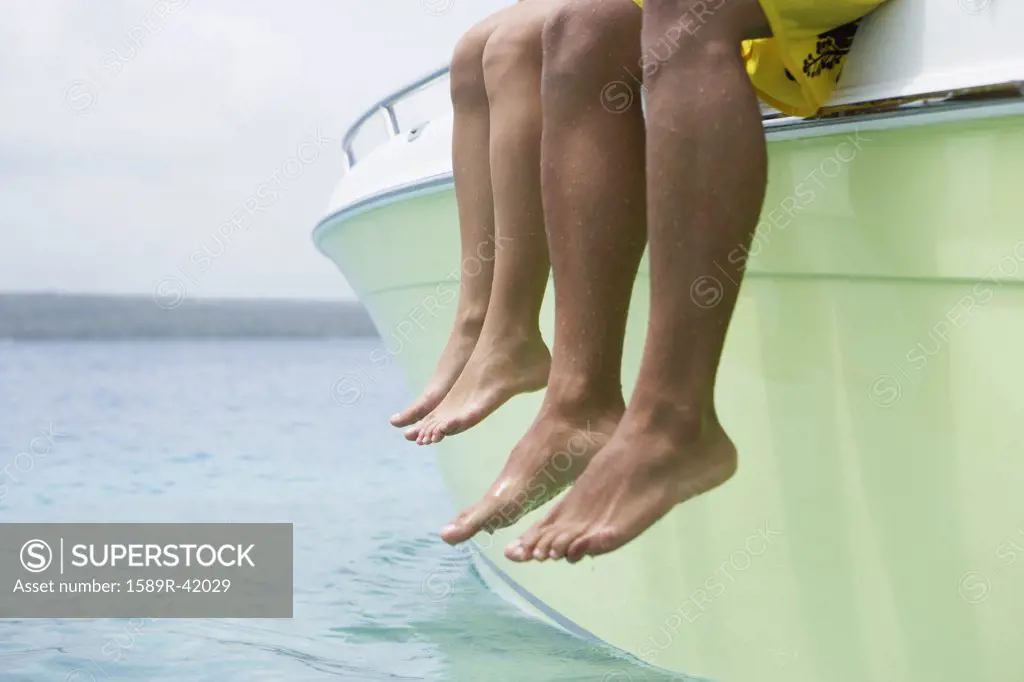 South American couple dangling feet off of boat