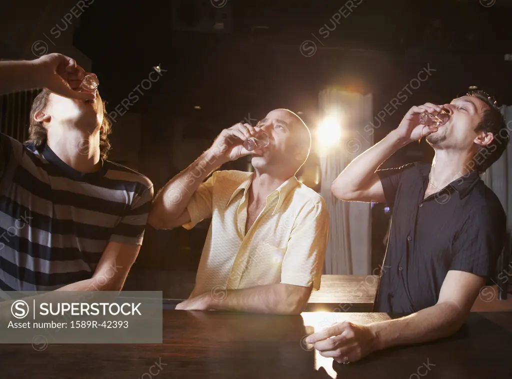 Hispanic men drinking shots at bar