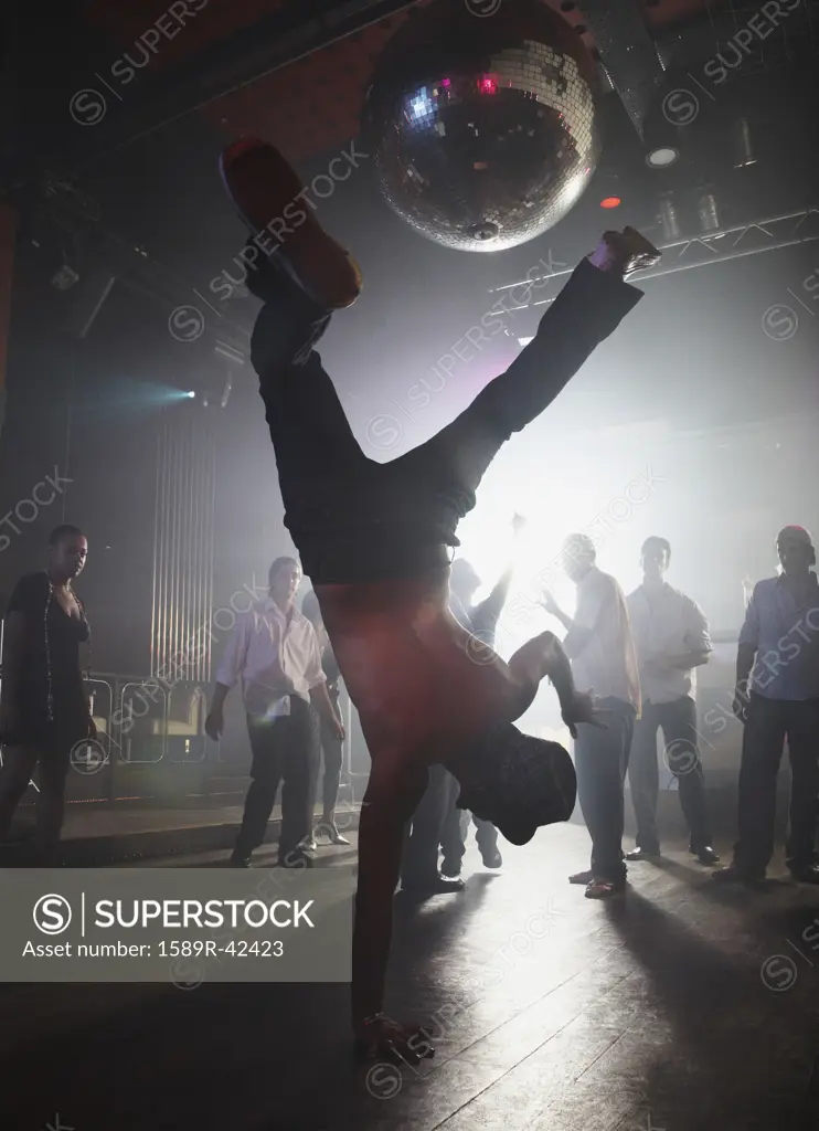 Hispanic man performing handstand at night club