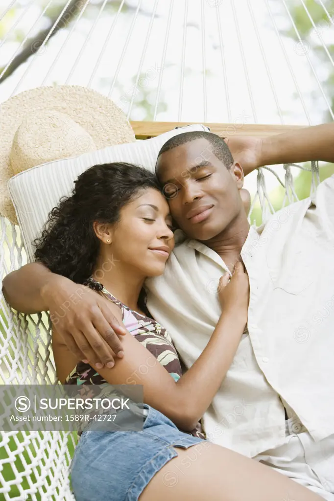 African American couple sleeping in hammock